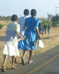 3 children walking along the side of a road